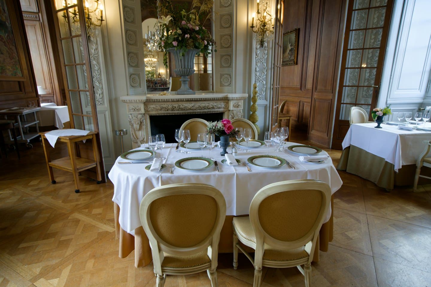 Sala da pranzo formale apparecchiata con stoviglie e centrotavola floreale.
