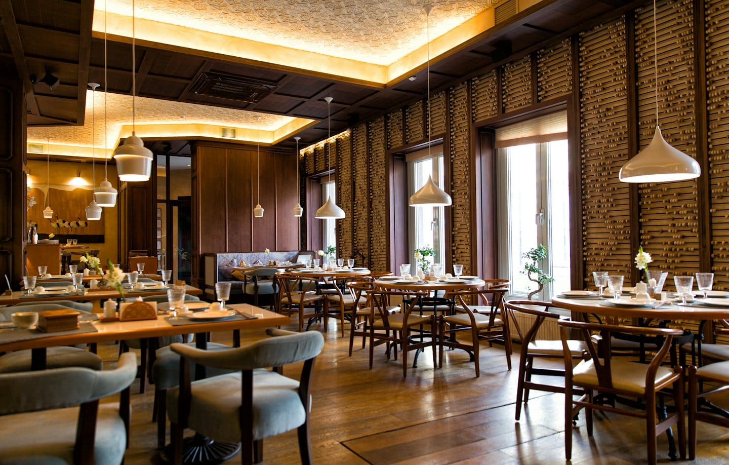 Sala da pranzo con tavoli e sedie vicino a grandi finestre.